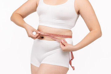 Young, beautiful woman with excess weight measuring her waist on a white background. Perfect for...