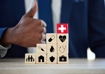 Hands, building blocks and symbol for insurance in office with thumbs up for assets, health or life. Person, agent and wood toys with yes, property and icon for risk cover for real estate at company