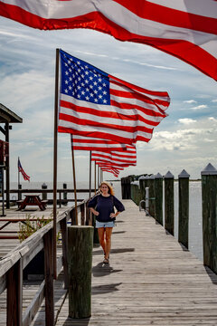 Crisfield, Maryland, USA A woman stands on the city fishing pier with American flags.