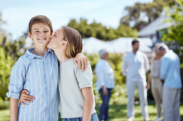 Fototapeta premium Happy children, siblings or hug with kiss on cheek in nature for outdoor weekend, holiday or bonding together. Young kids, brother or sister with smile for family love, youth or childhood in backyard