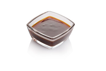 A small square glass bowl filled with rich brown sauce on a white background in a minimalist setting