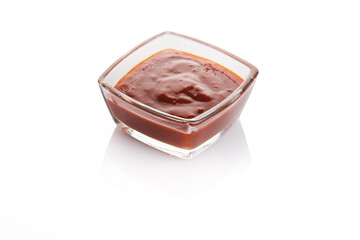 Deliciously rich barbecue sauce in a square glass bowl on a clean white surface, highlighting its texture and color