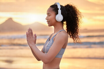 Woman, yoga and headphones at beach, sunset and profile with smile for music, mindfulness and peace. Person, girl and meditation with namaste, balance and streaming subscription by sea in Colombia