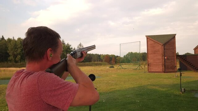 A middle-aged European shooter confidently hits clay pigeons at a shooting club