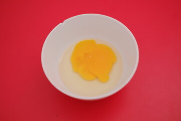 Egg yolks in a white bowl on a red background
