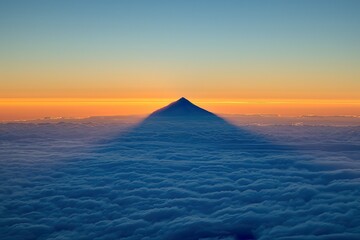 Fototapeta premium Rainer casts a dramatic shadow over clouds at sunrise, showcasing natural beauty and early morning tranquility