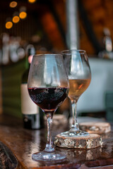 two wine glasses on wooden table red wine and white wine with bottle in the background in rustic country house