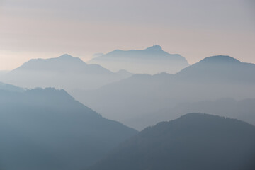 Serene alpine landscape at dawn in Gailtal Alpen, Carinthia, Austria, Europe. Silhouette of majestic hazy mountain ridges of Julian Alps. Peaceful tranquil atmosphere in Austrian Alps. Wanderlust