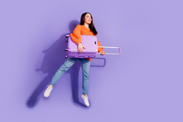 Photo of lovely positive glad girl wear trendy orange clothes hold bag look empty space isolated on violet color background