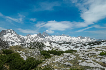 Panoramic aerial view of majestic snow capped mountain peak Hoher Dachstein seen from Lackner Miesberg in Ramsau, Styria, Austria. Hiking trail in Austrian Alps in spring. Wild Schladminger Tauern