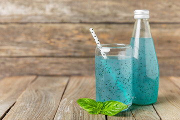 Diet detox cocktail with basil and chia seeds in a glass jar and a glass on a textured background....