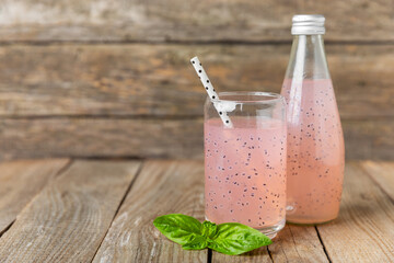 Diet detox cocktail with basil and chia seeds in a glass jar and a glass on a textured background....