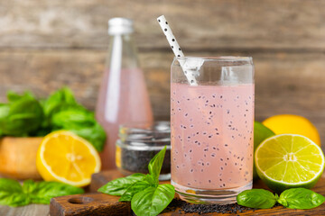 Diet detox cocktail with basil and chia seeds in a glass jar and a glass on a textured background....