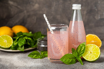 Diet detox cocktail with basil and chia seeds in a glass jar and a glass on a textured background....