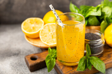 Diet detox cocktail with basil and chia seeds in a glass jar and a glass on a textured background....
