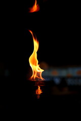 A captivating photograph of a martini glass filled with alcohol, topped with dancing flames, set against a dark background featuring a couple sitting at a table.