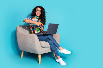 Naklejka premium Photo of pretty lovely funny woman wear stylish clothes sit armchair showing netbook isolated on blue color background