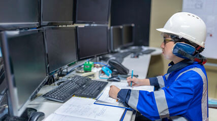 Inside the large Industry Factory Female Computer Engineer Works on Personal Computer She coding program for control machine,Thailand people work on fours monitors,Programmer working with serious