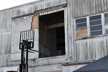 Forklift reaching tall warehouse door.