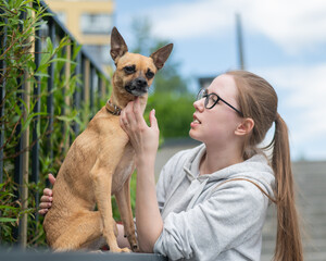 Young Caucasian woman and cute little dog walking. 