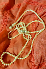 Pearl decoration on coral fabric. Fashion background design, photography. Textile, fabric template,  modern new