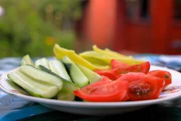 Sliced Cucumbers, Tomatoes And Bell Peppers On A Plate On A Table On A Summer Day On Vacation
