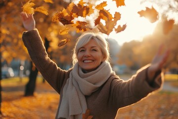 Happy mature woman throw up the autumn leaves in the park
