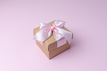 Close view of gift box on pastel pink backdrop. Creative holiday concept.