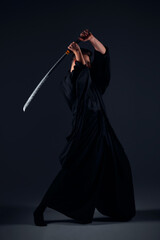 Samurai ninja warrior in kimono in attack pose with katana sword. dark room. sword shine. fighter. japanese culture