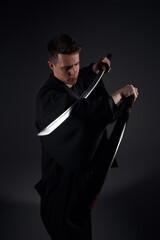 Samurai ninja warrior in kimono in attack pose with katana sword. dark room. sword shine. fighter. japanese culture