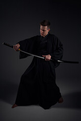 Samurai ninja warrior in kimono in attack pose with katana sword. dark room. sword shine. fighter. japanese culture