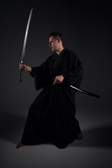 Samurai ninja warrior in kimono in attack pose with katana sword. dark room. sword shine. fighter. japanese culture