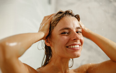A cheerful woman enjoying a rejuvenating and refreshing shower, radiating vibrant happiness and a...