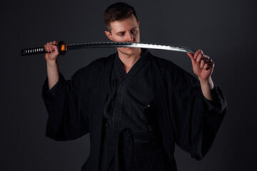 Samurai ninja warrior in kimono in attack pose with katana sword. dark room. sword shine. fighter. japanese culture
