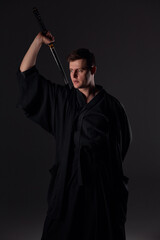 Samurai ninja warrior in kimono in attack pose with katana sword. dark room. sword shine. fighter. japanese culture