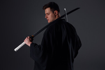 Samurai ninja warrior in kimono in attack pose with katana sword. dark room. sword shine. fighter. japanese culture