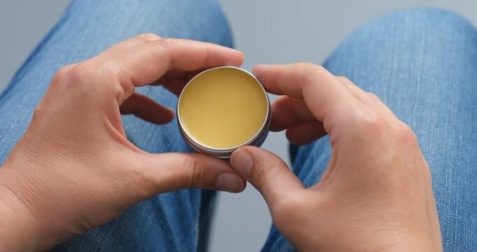 Balm in a tin can in woman hands.