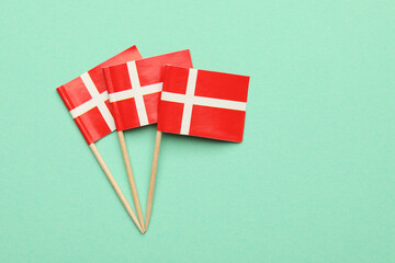 Fototapeta premium Small paper flags of Denmark on turquoise background, top view. Space for text