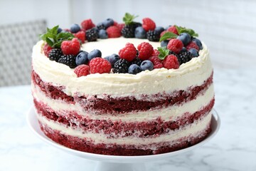 Tasty sponge cake with different berries and mint on white marble table, closeup