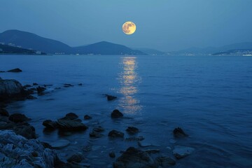 Large orange moon rising over a calm ocean at night