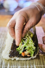 Crafting a delicious sushi roll with fresh ingredients at a bustling food market during a sunny afternoon