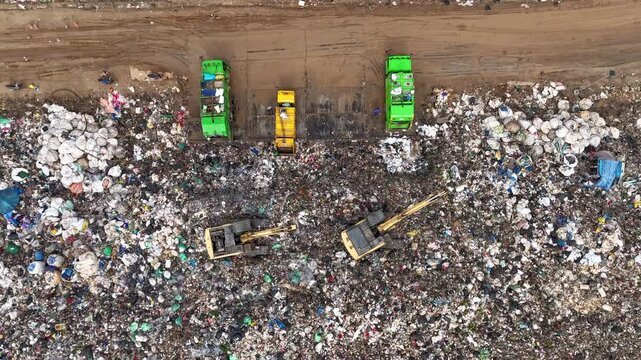 Time-lapse aerial view of large garbage, waste, landfill, workers sorting garbage in a landfill, garbage trucks dumping garbage that causes global warming pollution.
