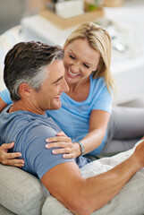Fototapeta premium Relax, laughing and happy couple in home for love, comedy and funny joke on sofa. Mature man, woman and smile in living room for connection, romance and conversation for healthy relationship together