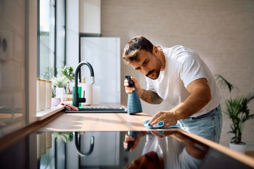 Young man cleaning  kitchen at home.