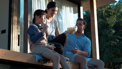 Father, mother and daughter do activity at terrace with garden view outside house. Parent use outdoor activity to communicate young generation about environment care cross generation gap. Divergence.