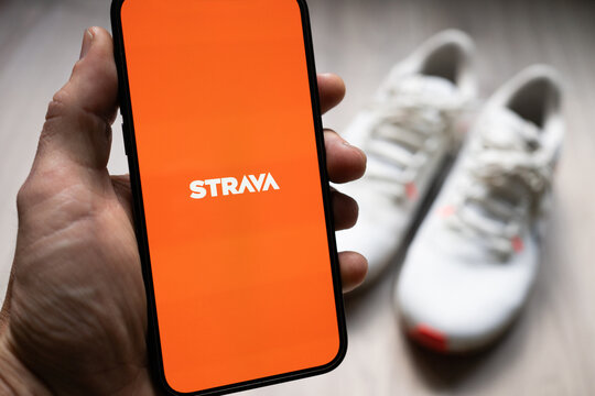 Person holding a phone with Strava app with a running shoes in the background