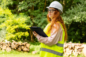Forestry engineer worker in protective workwear, front of wood lumber cut tree. Ecologist volunteer...