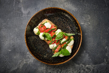 close-up view of a delicious caprese bruschetta with ripe tomatoes, fresh basil, and creamy...