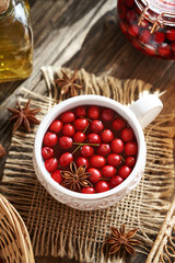 Herbal tea with fresh hawthorn berries in a white ceramic cup on a table