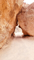 A narrow passage between two large rocks in a desert area